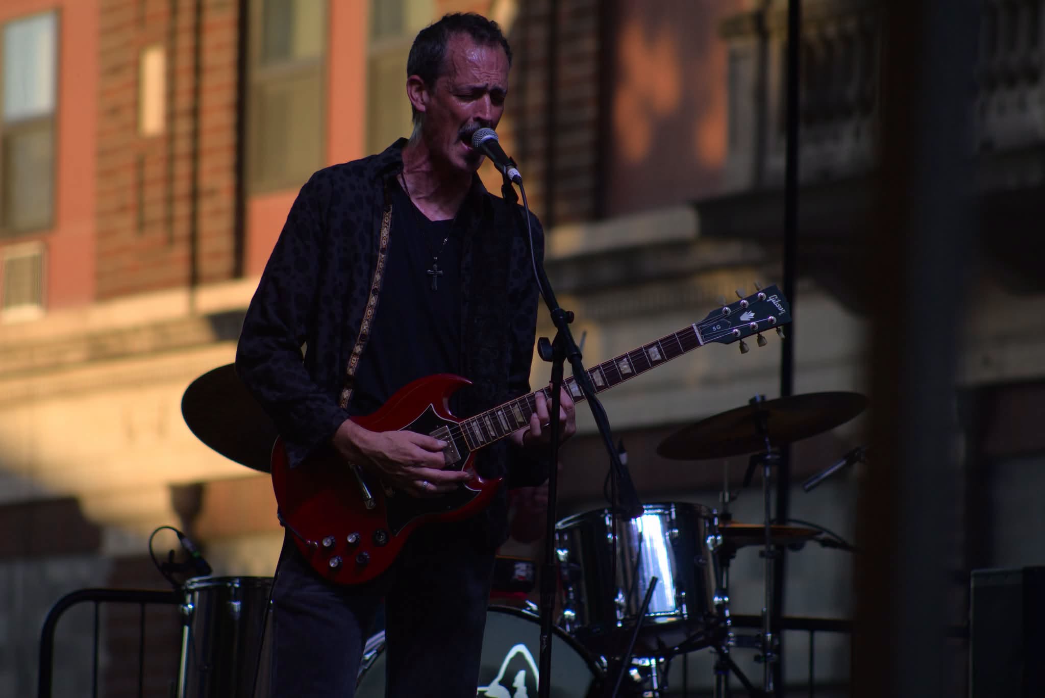 Jason Wells singing and playing a red electric guitar